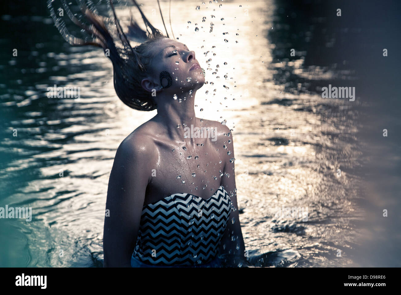 Woman throwing hair back in body of water Stock Photo