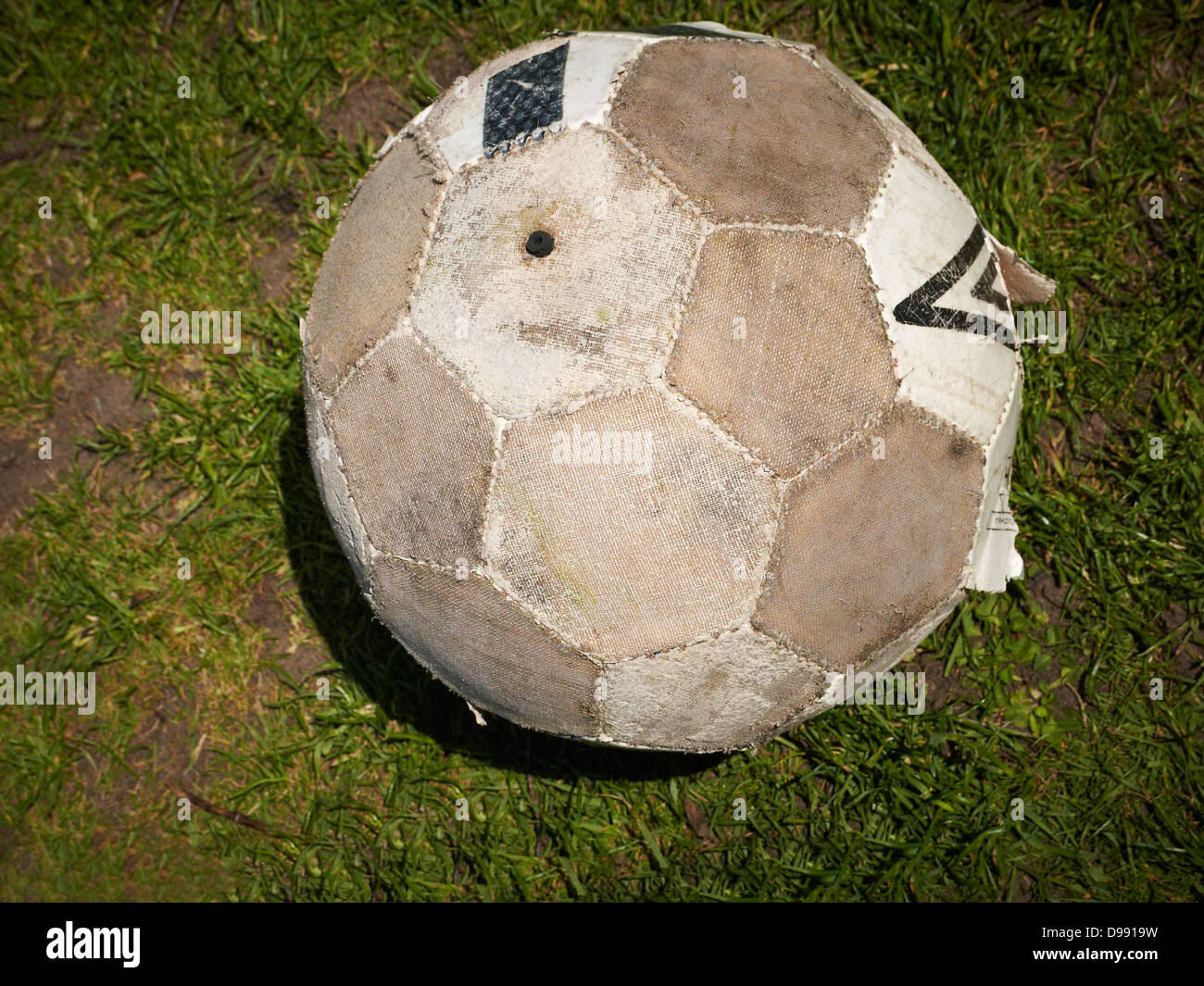 Worn out football on pitch Stock Photo