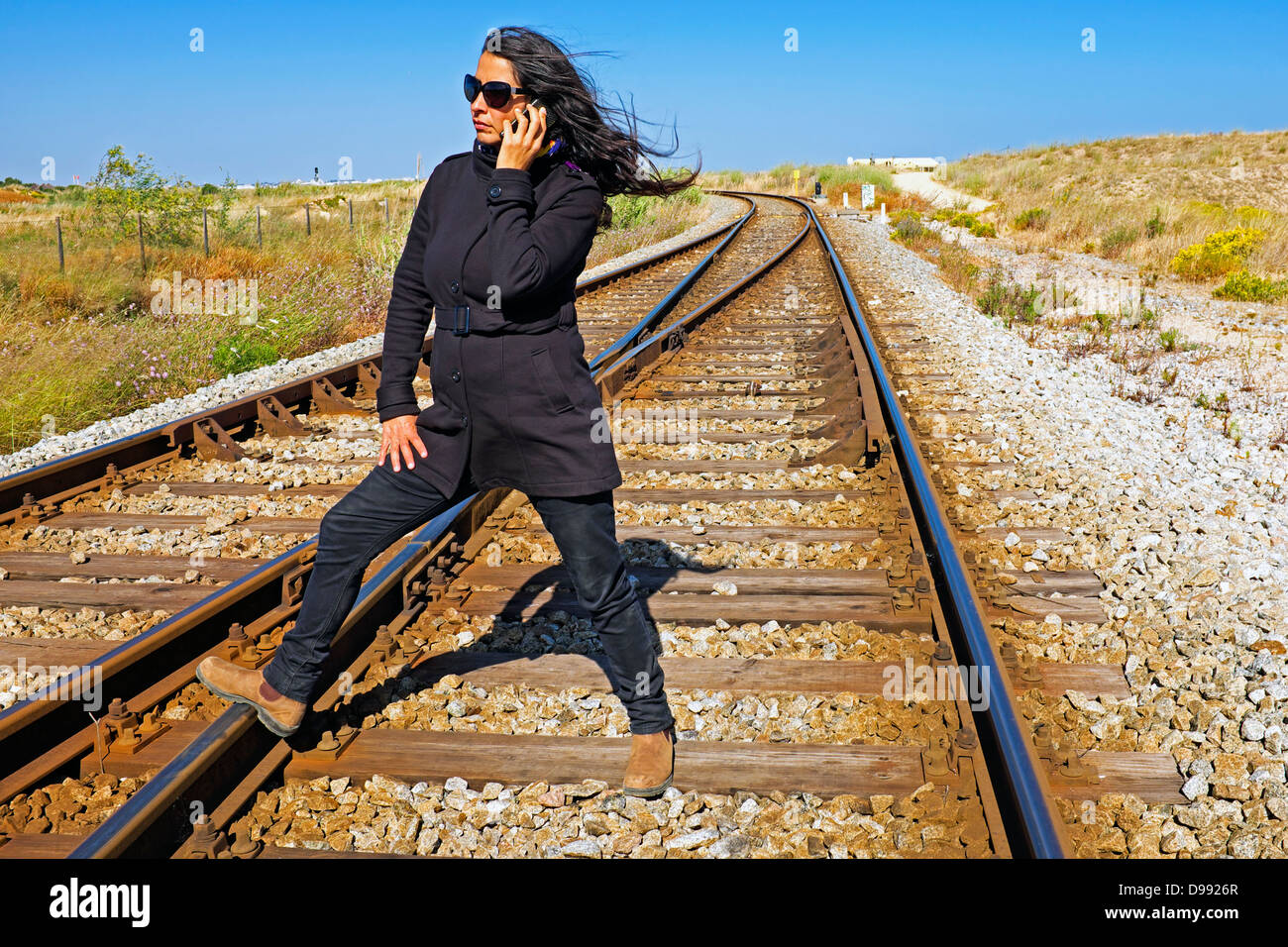 Beautiful woman phoning at a railroad track Stock Photo