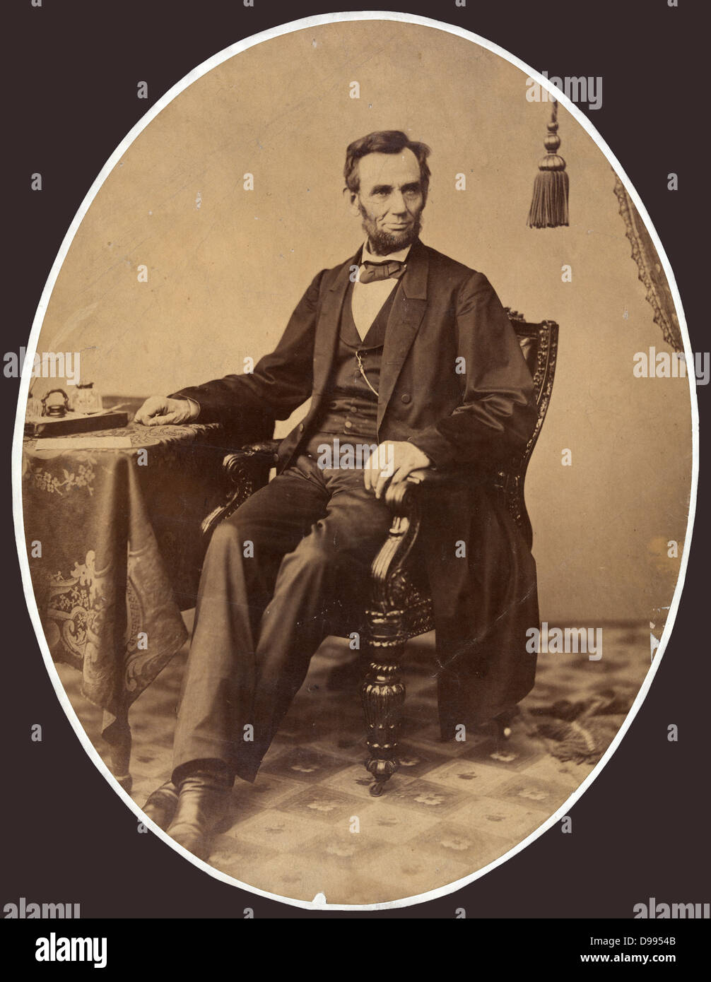 President Abraham Lincoln (1809-1865) in 1863, little more than a week before he gave the Gettysburg Address. Full-length oval portrait, seated with right arm resting on table, facing slightly right. Stock Photo