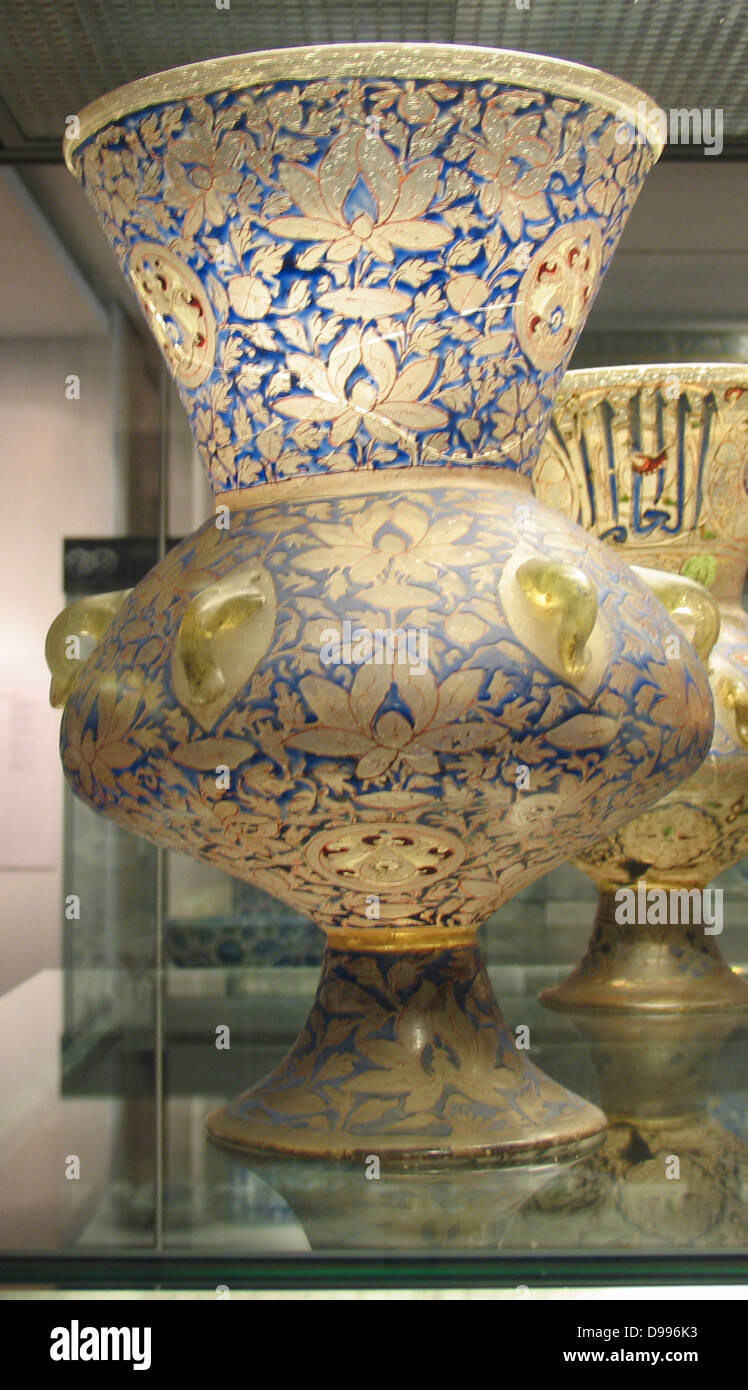 Mosque lamp. Mamluk dynasty, about AD 1350-55 From Cairo, Egypt. The lamp is also decorated with a bold inscription frieze containing the name and titles of Sayf al-Din Shaykhu al-Nasiri, and his heraldic device incorporating a red cup appears in the centre of the roundels on the neck and the underside of the lamp. Stock Photo