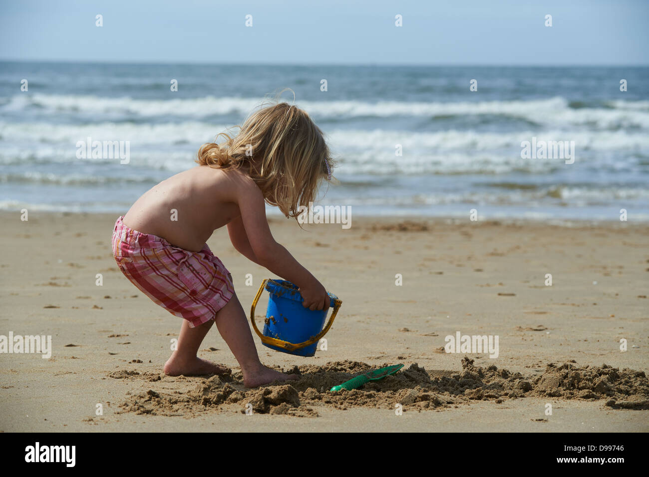 Toddler child blond girl playing in sand on beach Stock Photo