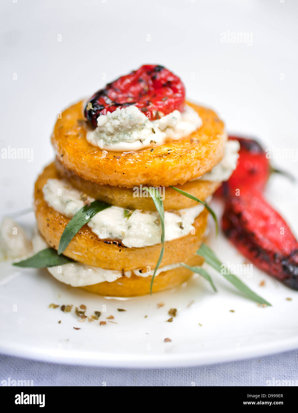 fried polenta stacked with feta cheese and herbs Stock Photo