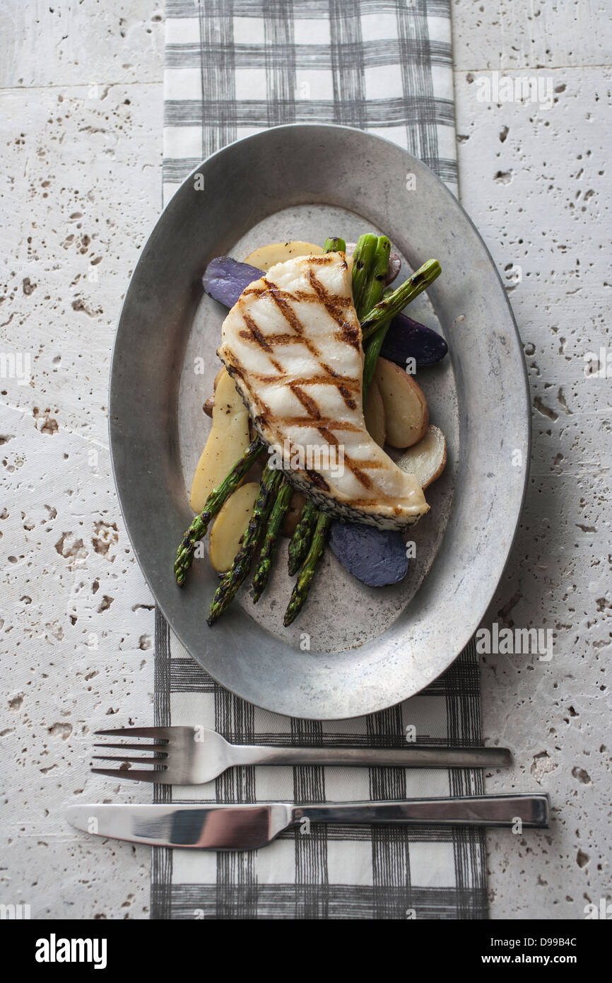 grilled halbut asparagus and potatoes on rustic metal plate Stock Photo