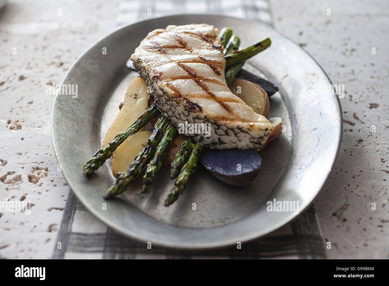 grilled halbut asparagus and potatoes on rustic metal plate Stock Photo