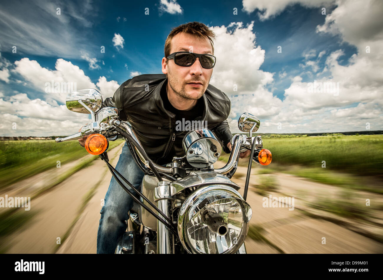 Biker in sunglasses and leather jacket racing on the road Stock Photo