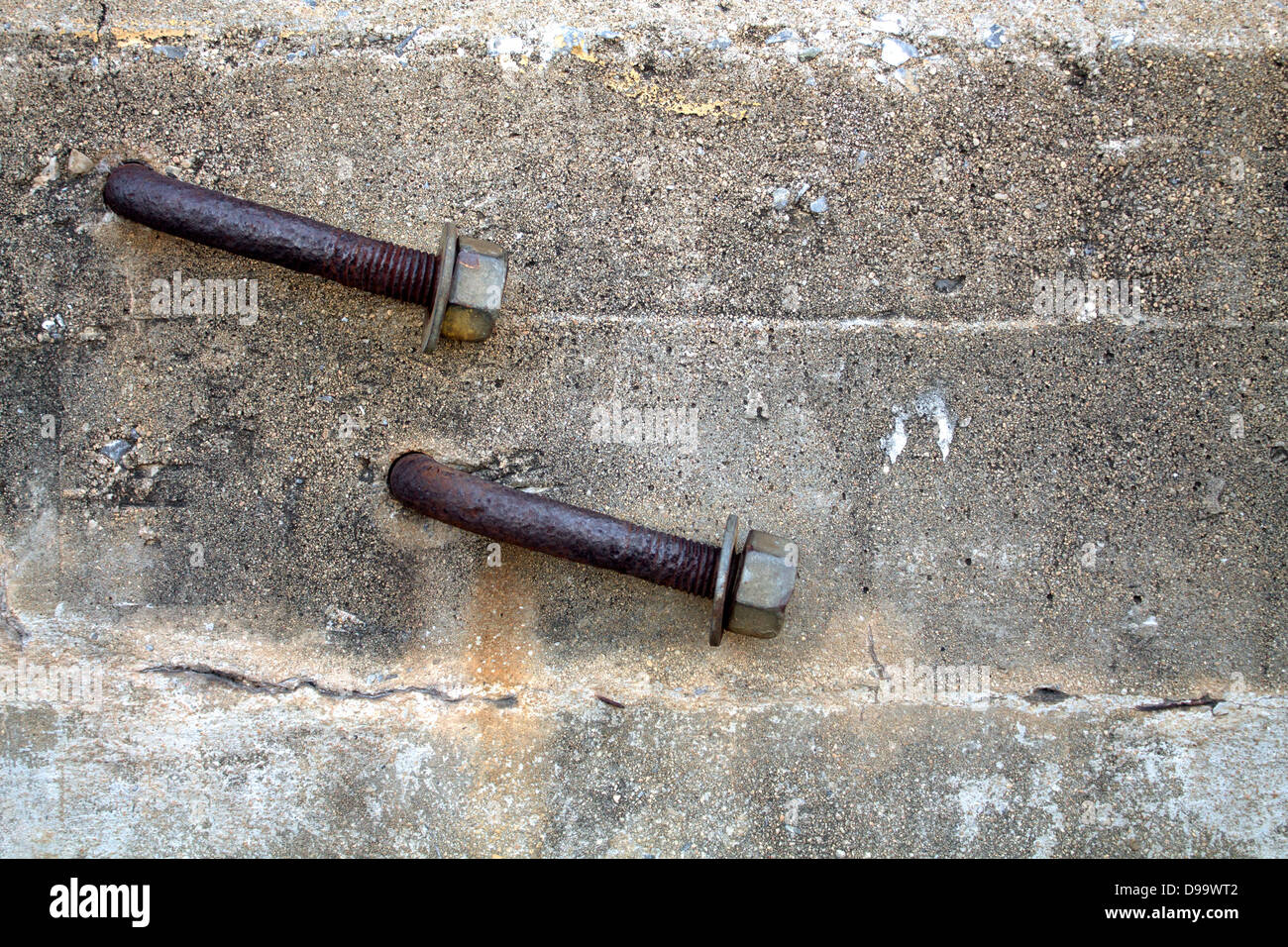 Two Rusty Bent Lag Bolt in Concrete. Stock Photo