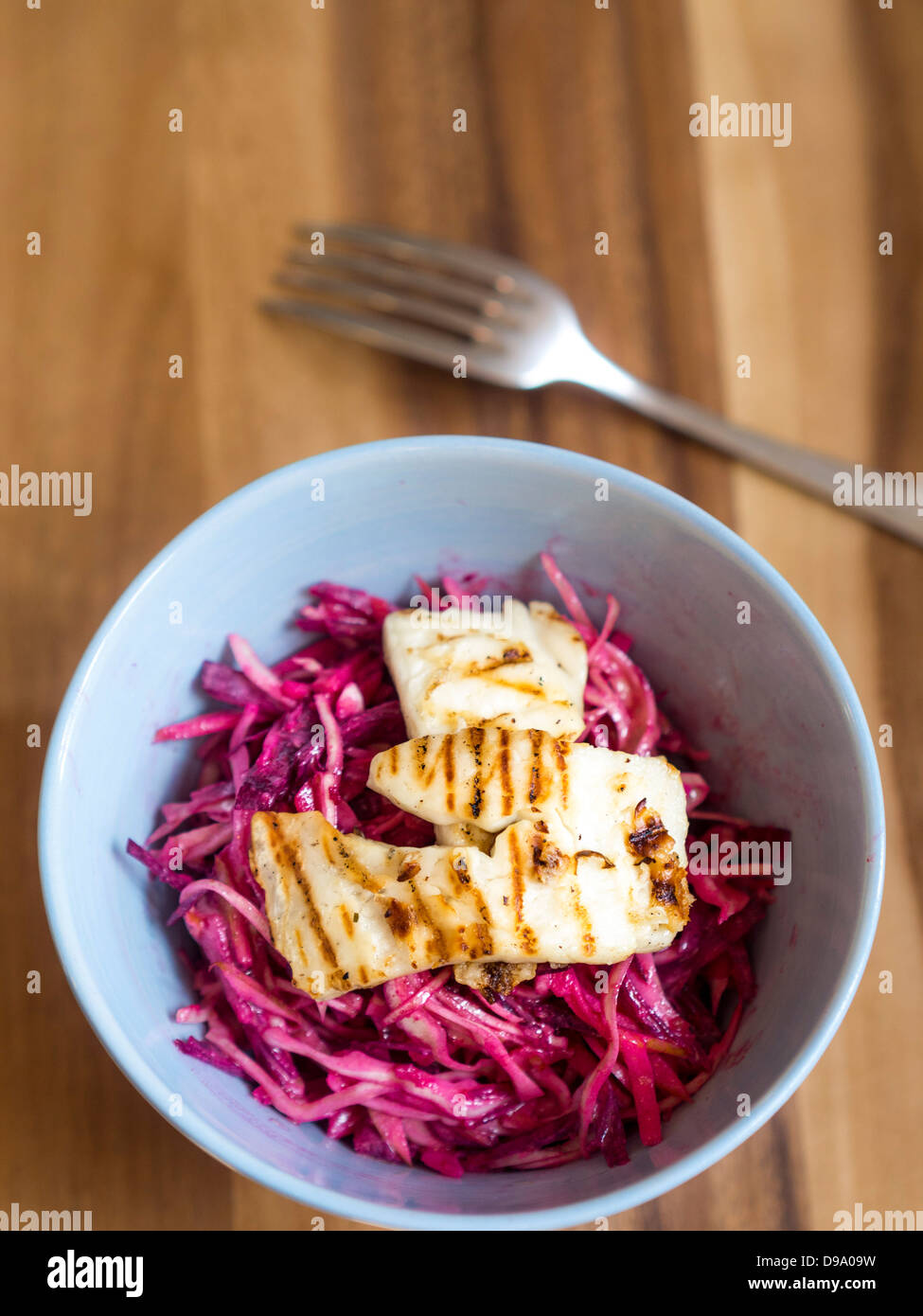 Raw cabbage, apple and beetroot slaw dressed in rice vinegar with grilled halloumi cheese Stock Photo