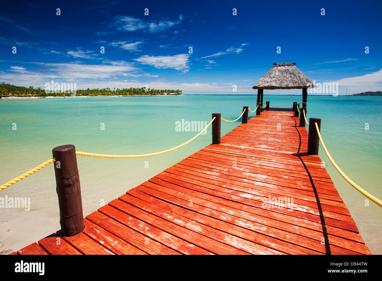Wooden red jetty extending to tropical green lagoon Stock Photo - Alamy