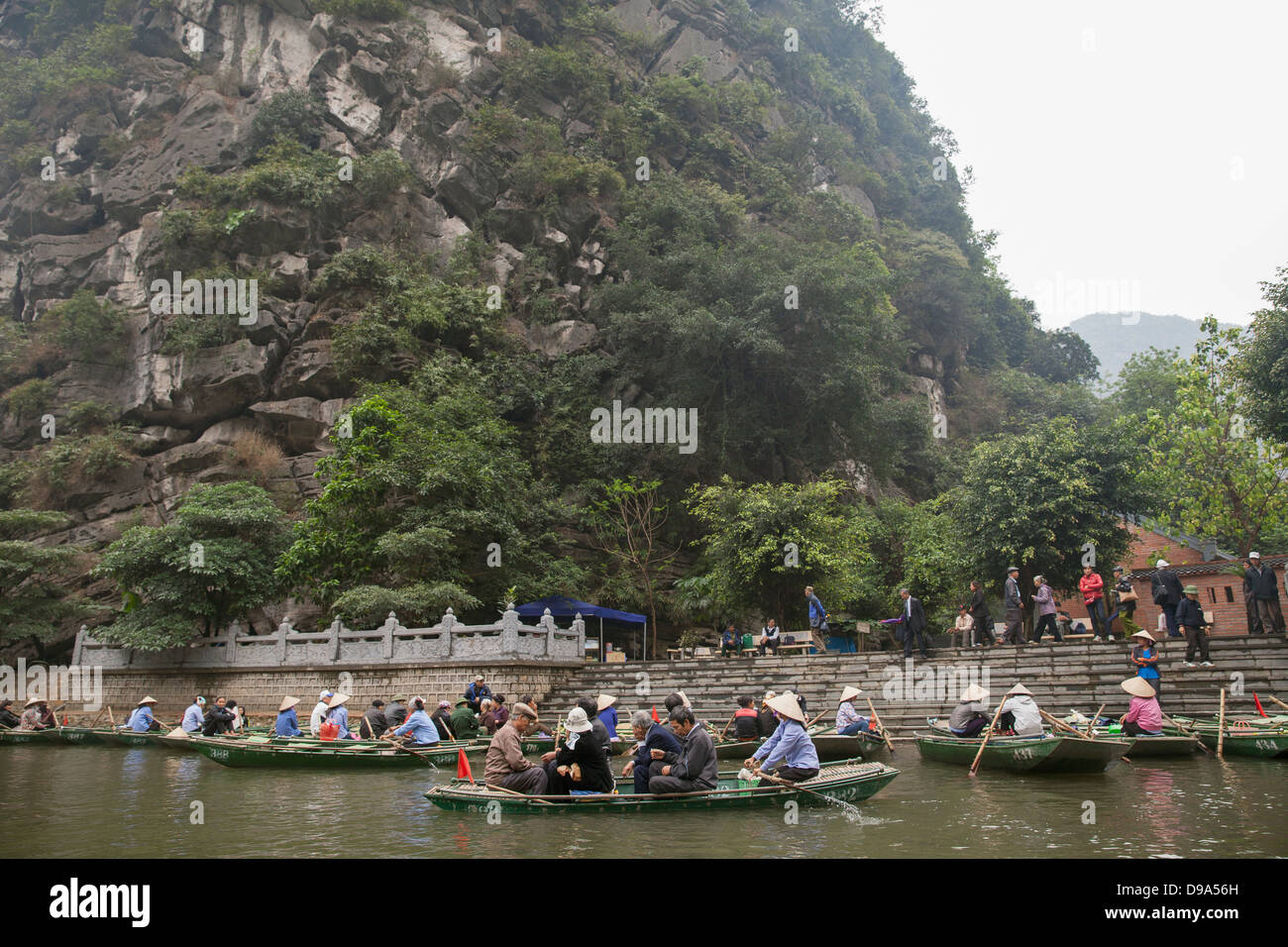Boats full of tourists at stop along the Trang An grottoes, Ninh Binh, Vietnam, Southeast Asia Stock Photo