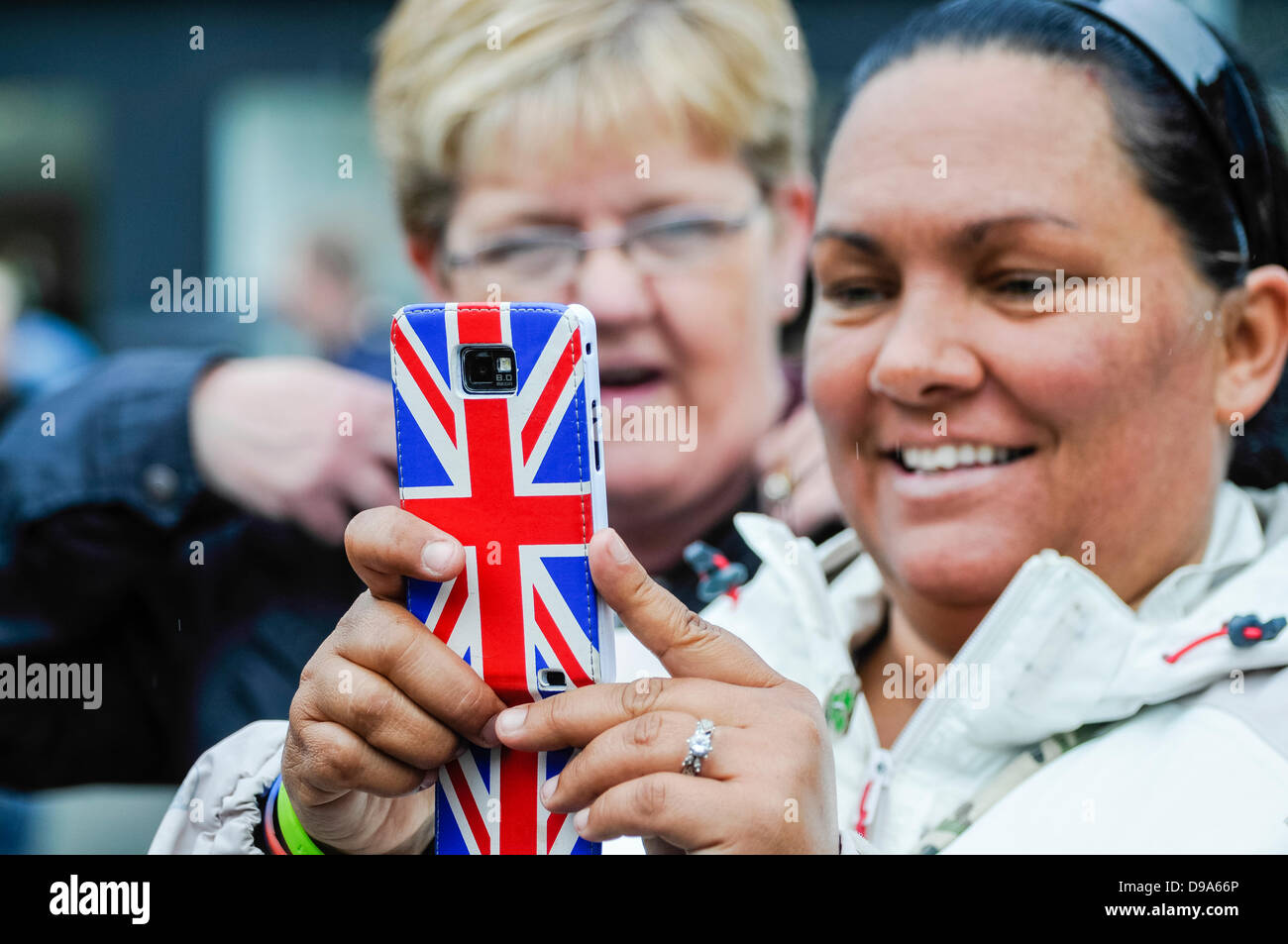 A woman takes a photograph using a mobile phone with a [upside down] Union Jack flag case Stock Photo