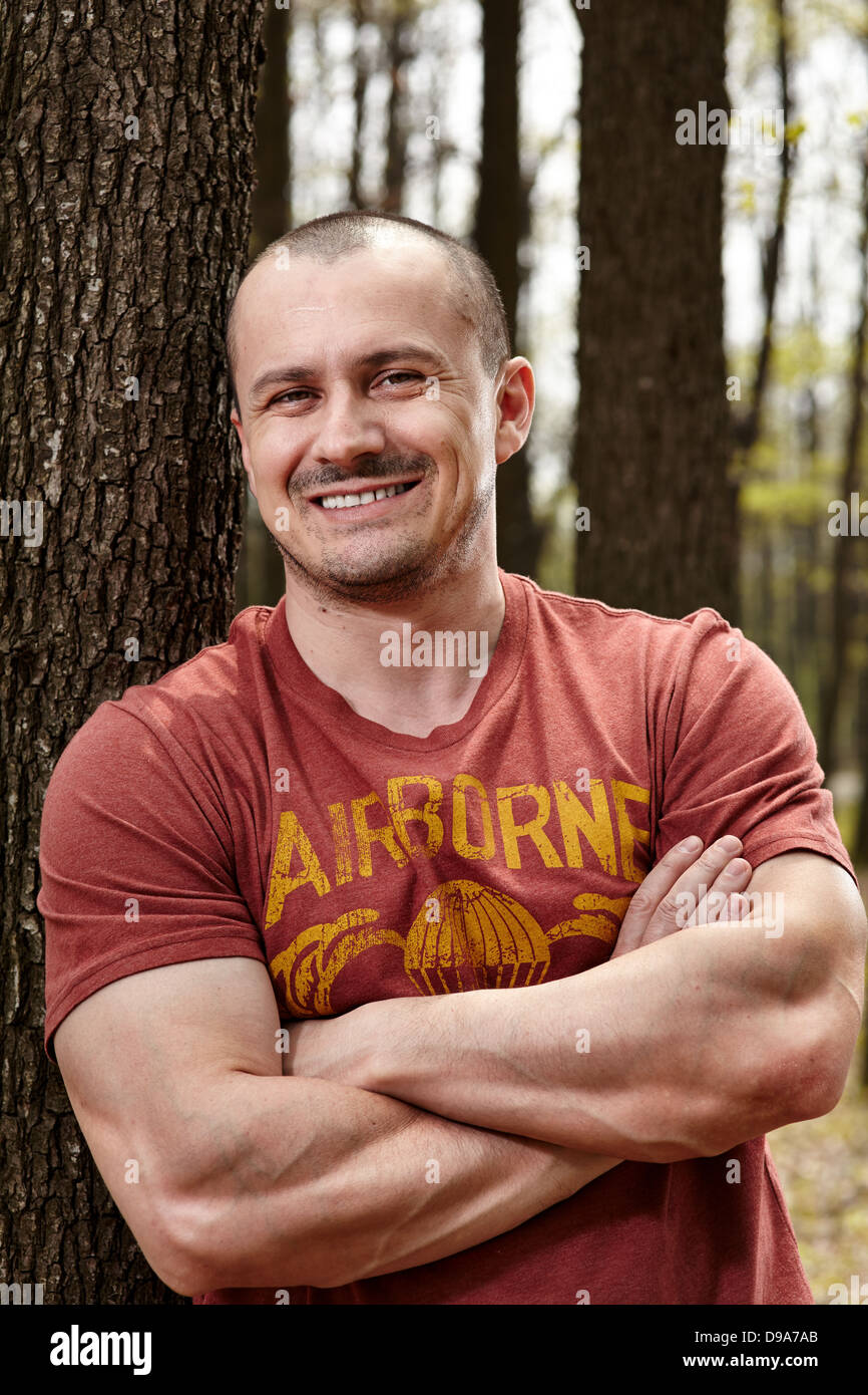 Closeup portrait of a handsome man leaning on a tree trunk Stock Photo