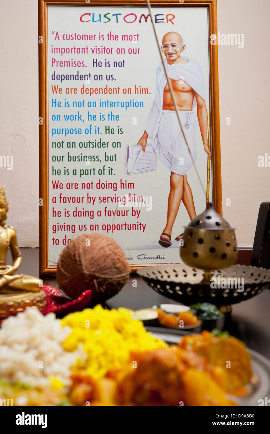 Mahatma Gandhi and a statement about the importance of the customer Indian Ethnical Food Vegetarian Thali in the foreground Stock Photo