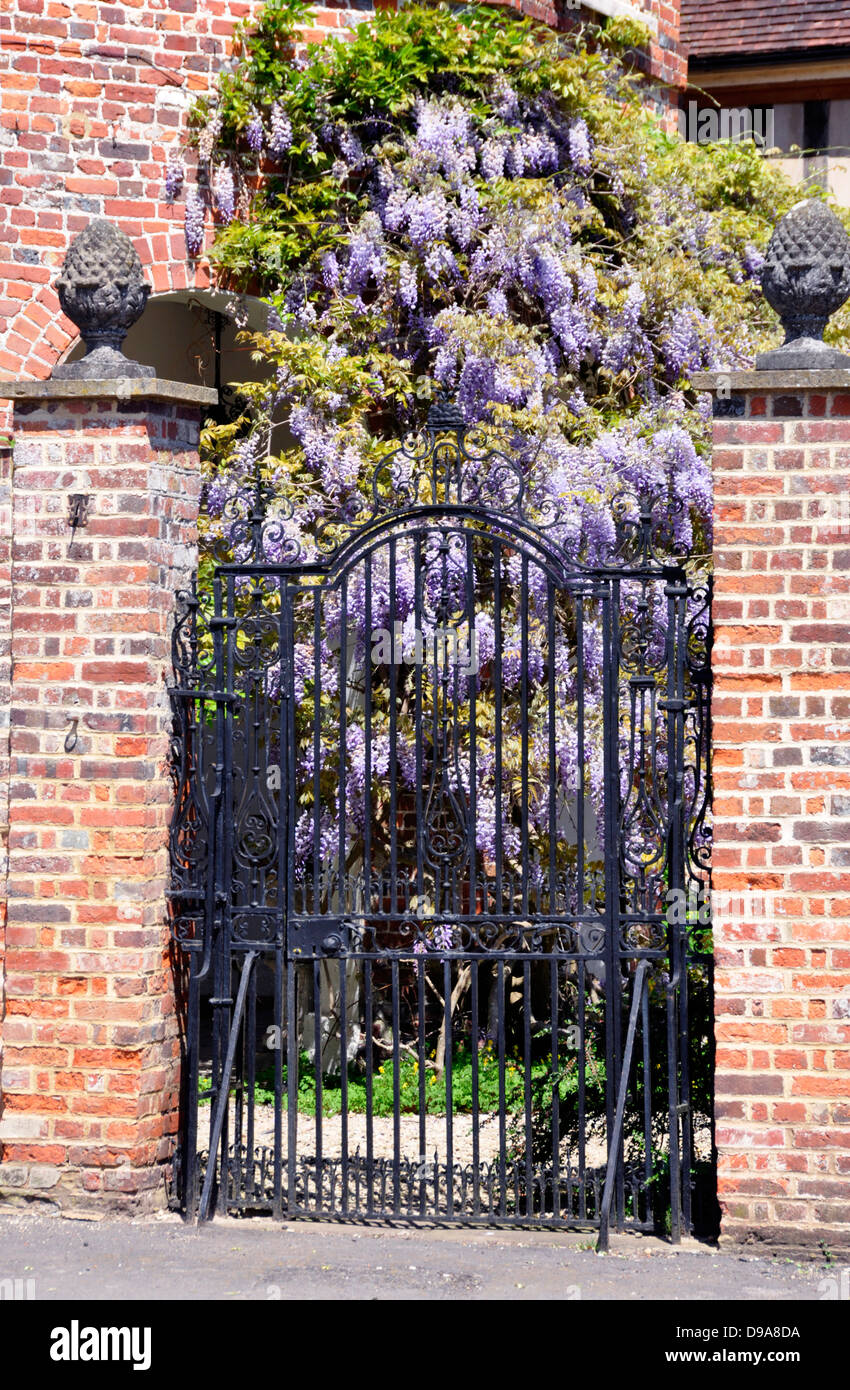 Bucks - Little Missenden - entrance gateway to the manor house - fine brick piers and wrought iron gate - wisteria bloom beyond Stock Photo