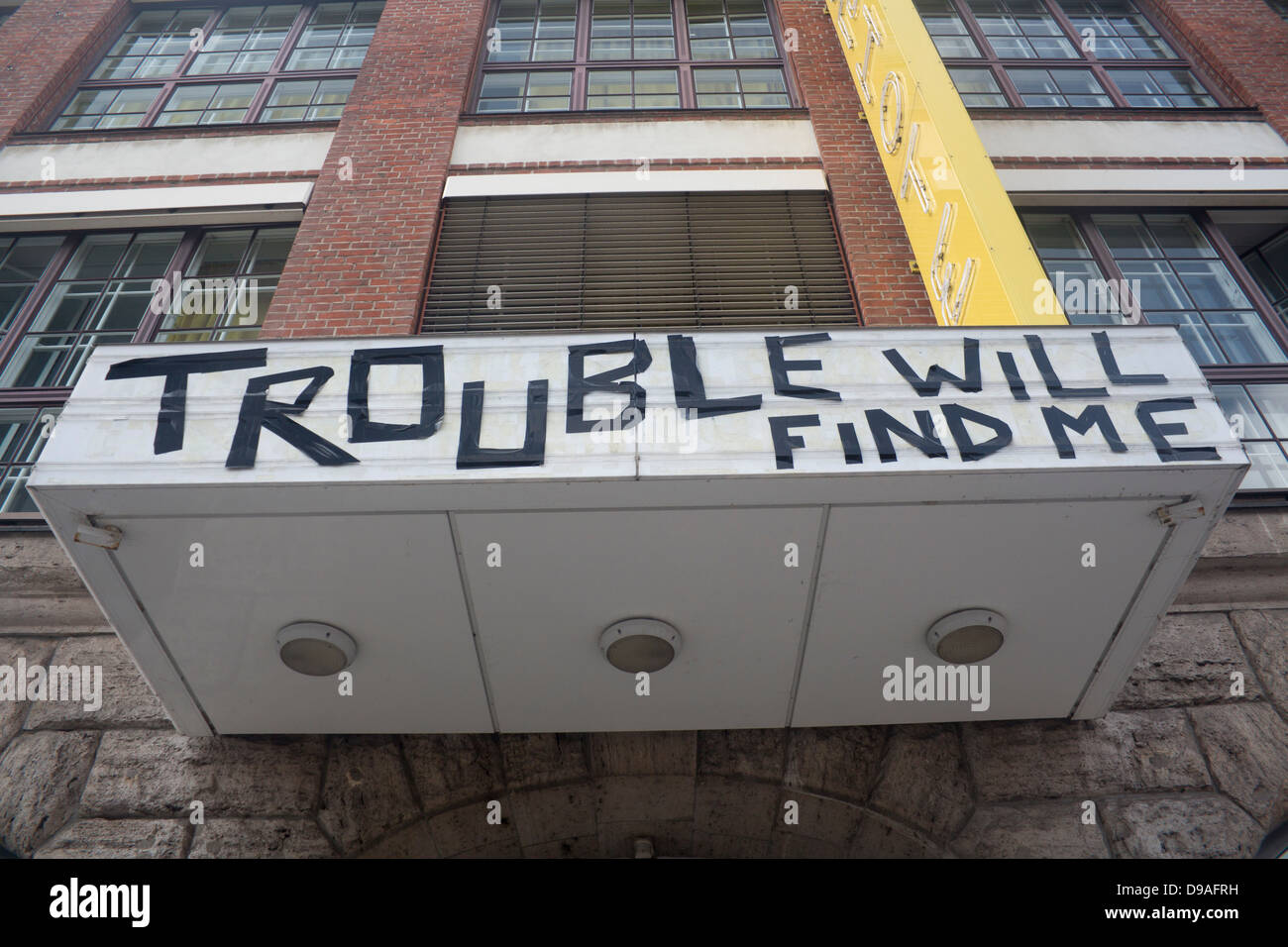 'Trouble Will Find Me' sign taped onto front of former hotel building Friedrichshain Berlin Germany Stock Photo