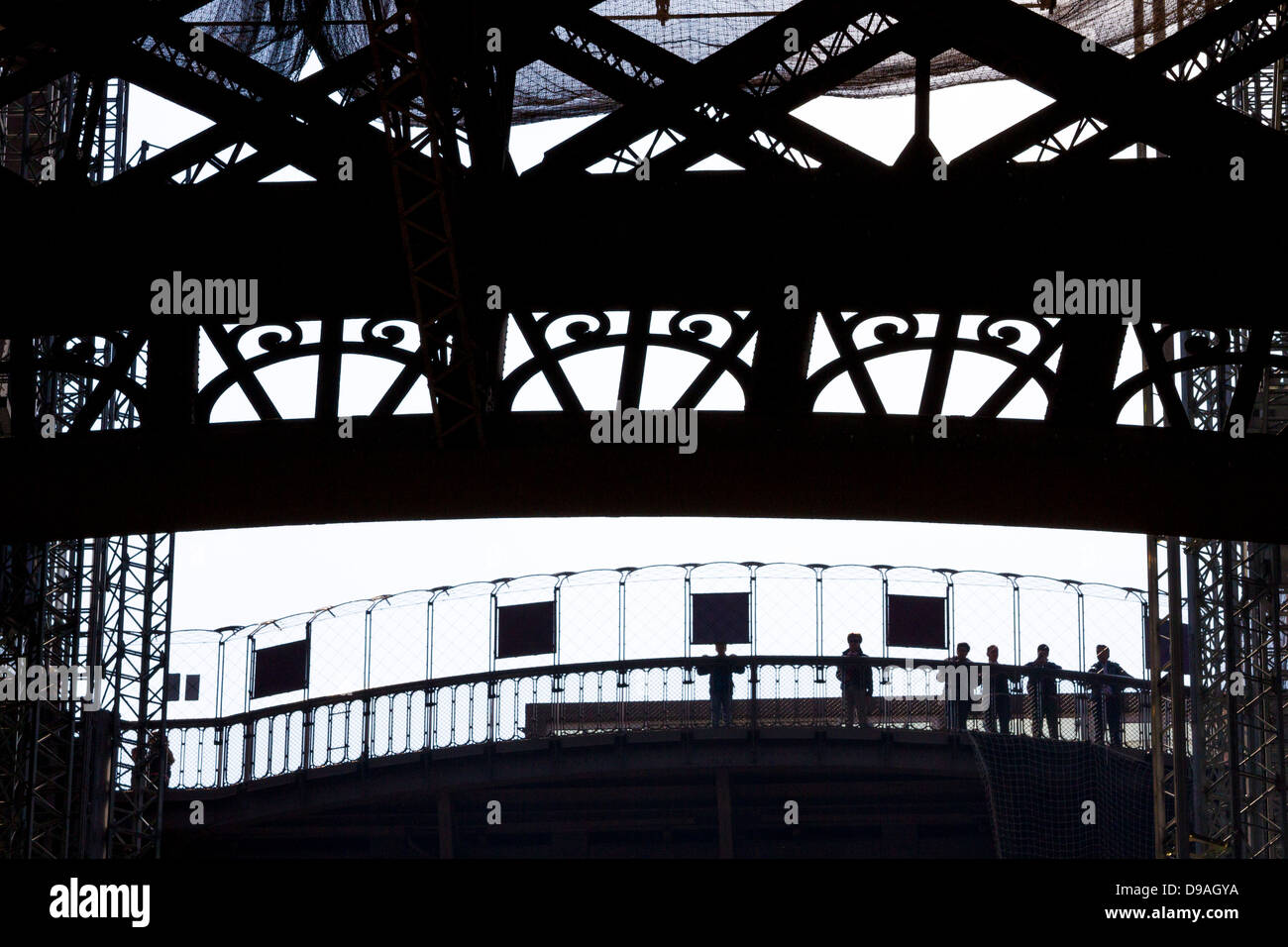 Silhouette of people looking out from first level platform of Eiffel Tower surrounded by decorative ironwork Stock Photo