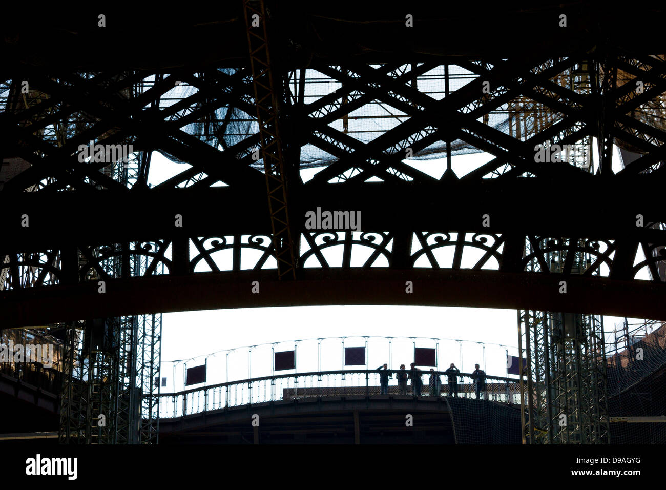 Silhouette of people looking out from first level platform of Eiffel Tower surrounded by decorative ironwork Stock Photo