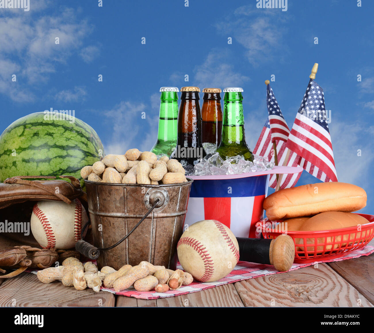 Picnic table ready for a Fourth of July celebration. Cold beer in an Uncle Sam Hat, watermelon peanuts, and baseball gear. Stock Photo