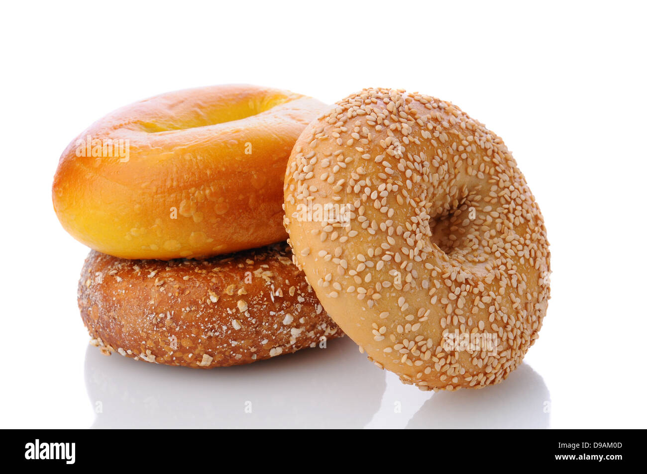 Three different bagels on a white surface with reflection. One each of an egg bagel, sesame seed, and mulit-grain Stock Photo