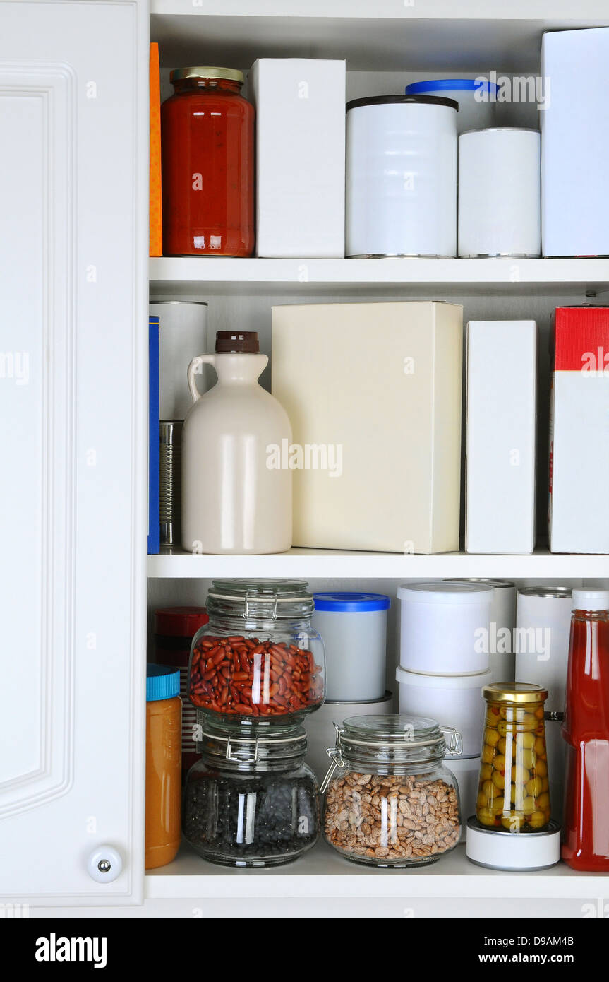 Closeup of a well stocked pantry. One door of the cabinet is open revealing canned goods, condiments, package foodstuffs Stock Photo