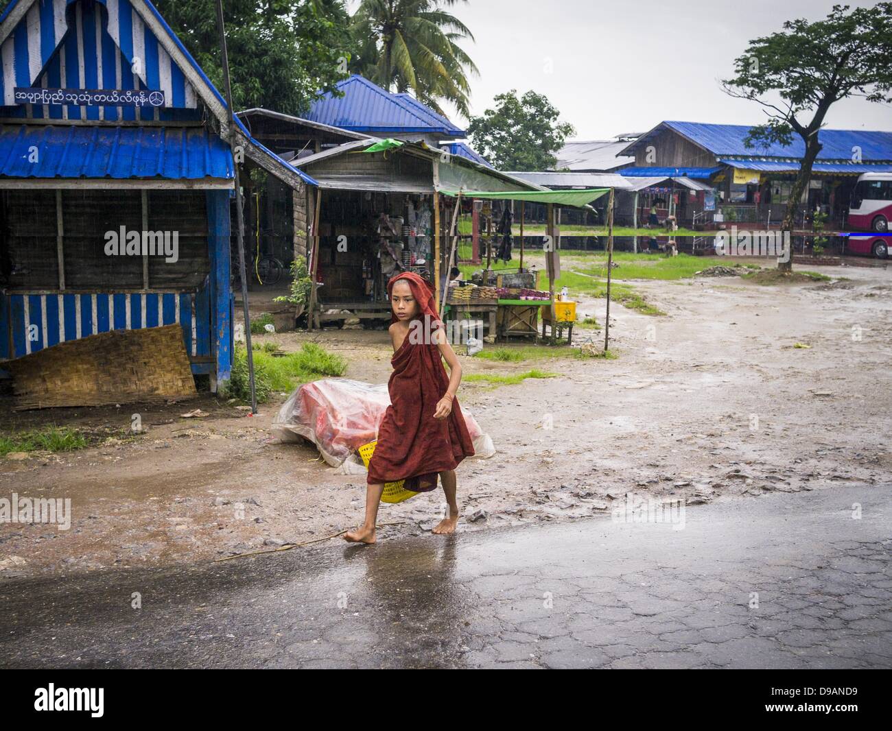 June 14, 2013 - Samalauk, Ayeyarwady, Union of Myanmar - A Buddhist novice walks through the rain along Highway 5 in Samalauk, Ayeyarwady, in the Irrawaddy delta region of Myanmar. Most Burmese men join the clergy at least once in the lives, sometimes for just a few weeks, other times for a lifetime commitment. This region of Myanmar was devastated by cyclone Nargis in 2008 but daily life has resumed and it is now a leading rice producing region. (Credit Image: © Jack Kurtz/ZUMAPRESS.com) Stock Photo