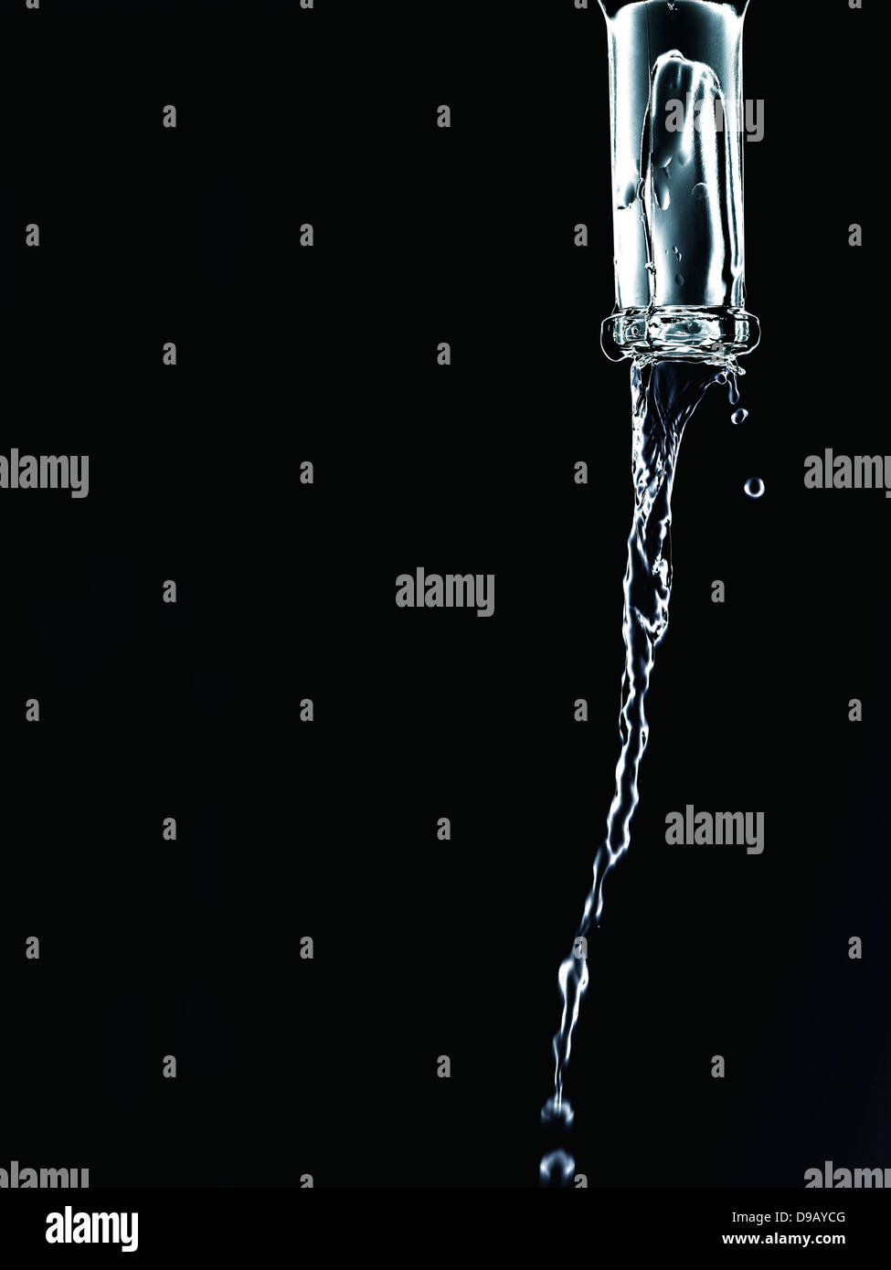 Water pouring from bottle against black background, close up Stock