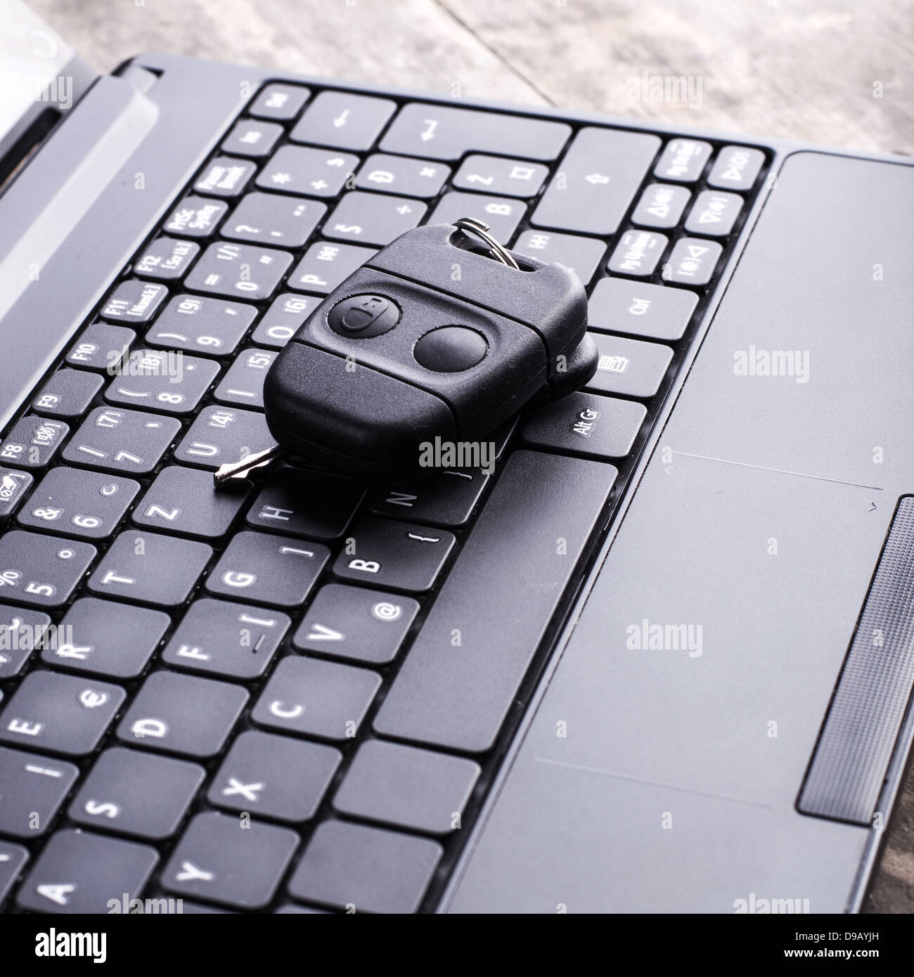 Car remote key and laptop in close up Stock Photo