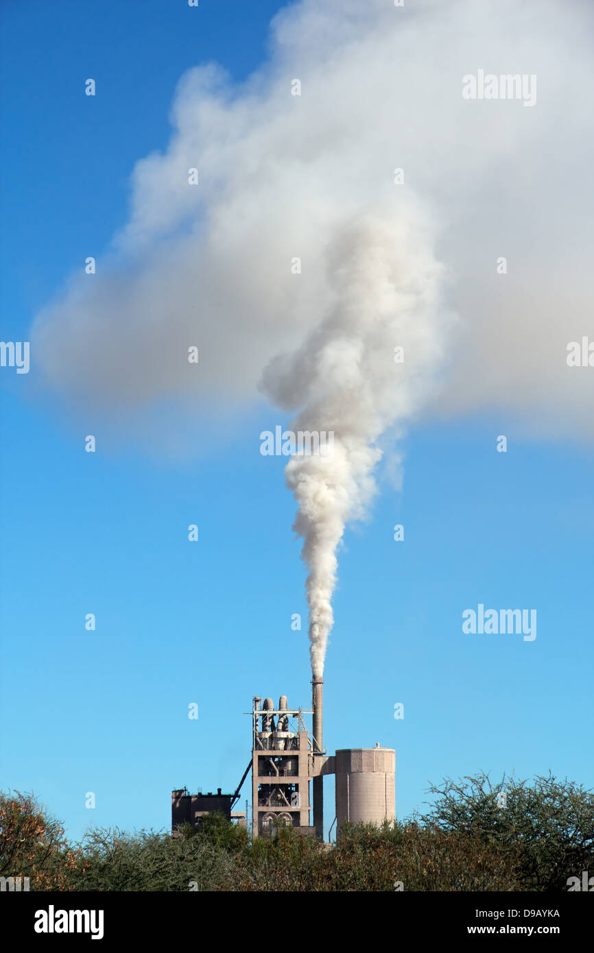 Smoke from an industrial plant drifting in the wind against a blue sky Stock Photo