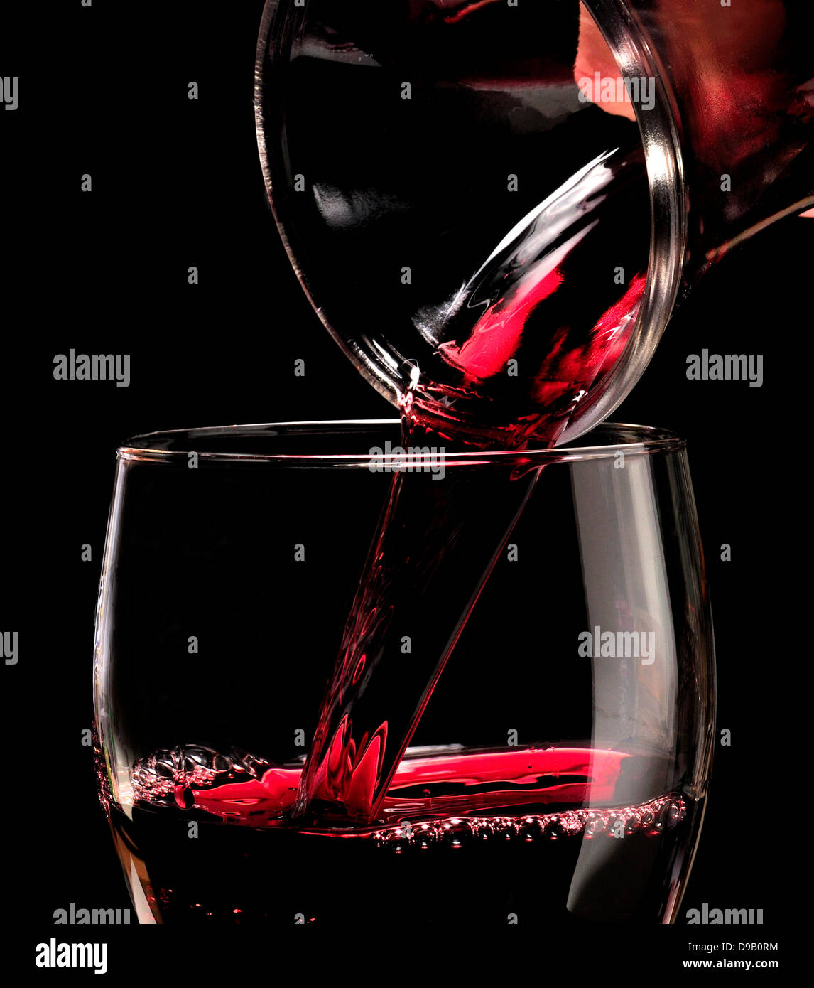 Red wine pouring into a glass from a carafe Stock Photo