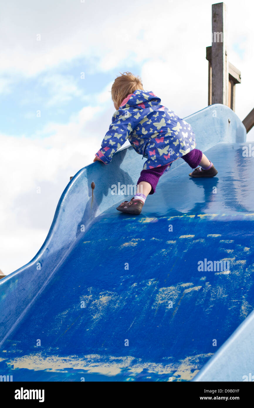 Germany, Girl playing on blue slide, smiling Stock Photo