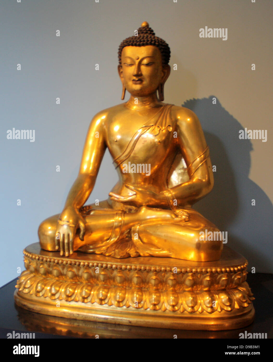 Seated Buddha, Chinese, 1740-1786 is shown just before his enlightenment.  Gilded copper. Stock Photo