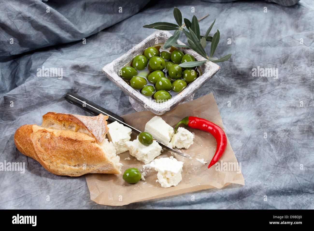Sheep's cheese with green olives in olive oil, chili and white bread on
