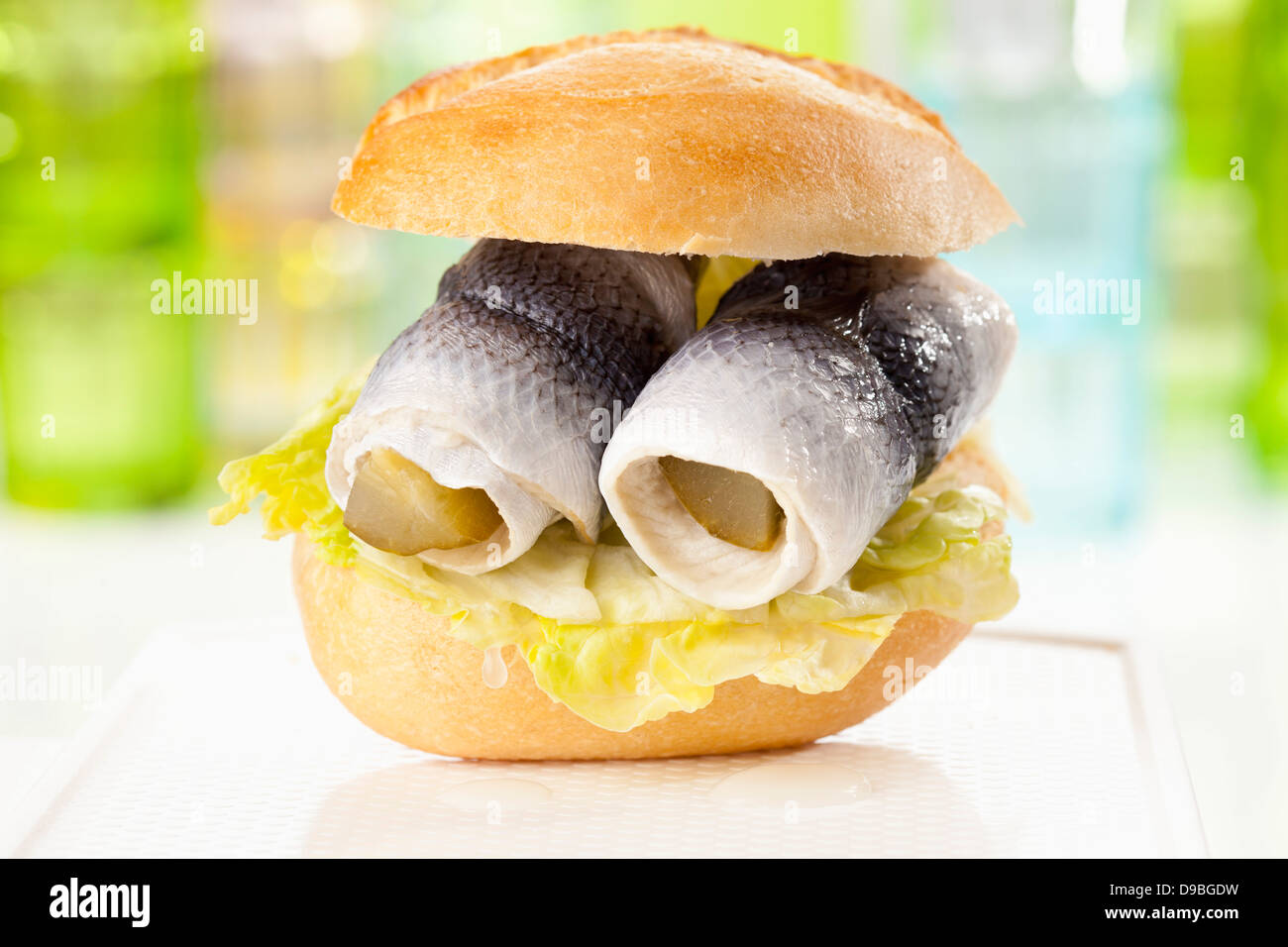 Bread roll with rollmop herring and pickled gherkin, close up Stock