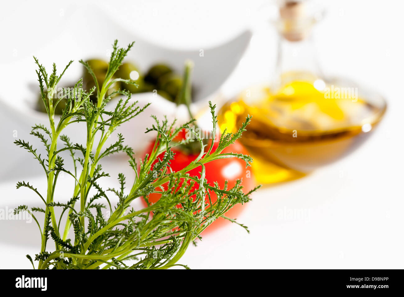 Olive herb with tomato, olives and olive oil on white background, close up Stock Photo