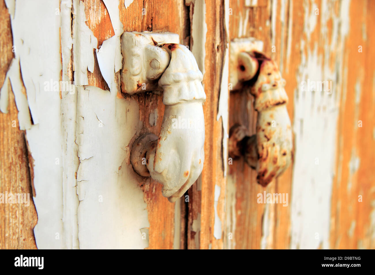 Architectural detail, peeling paint on a door with rusty door knockers
