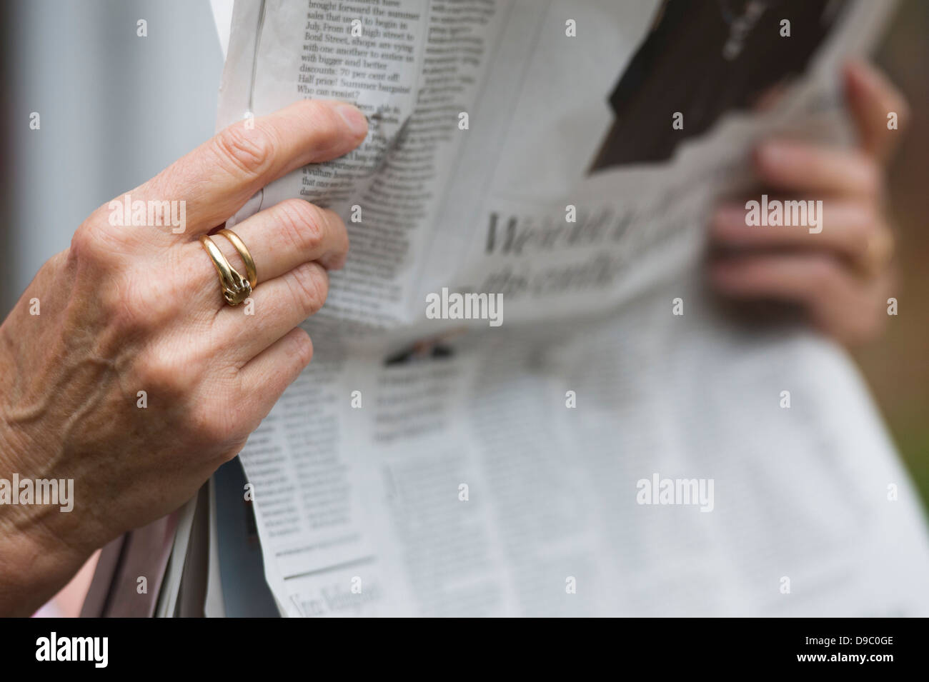 Senior womans hands holding newspaper. Selective focus. Stock Photo