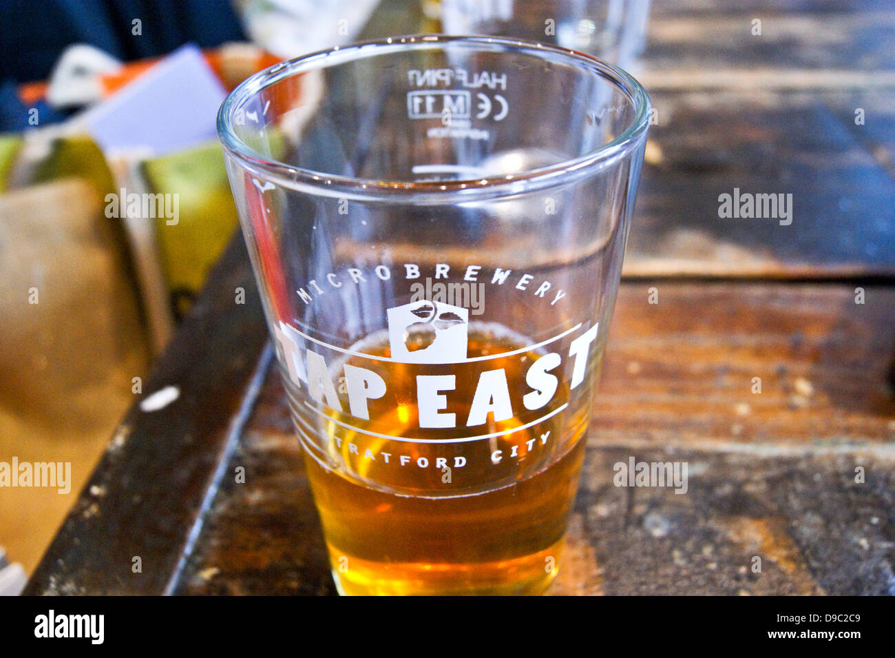 A pint of pale ale in a printed glass at Tap East bar, Westfield, Stratford, London, England pub table drinks glasses UK Stock Photo