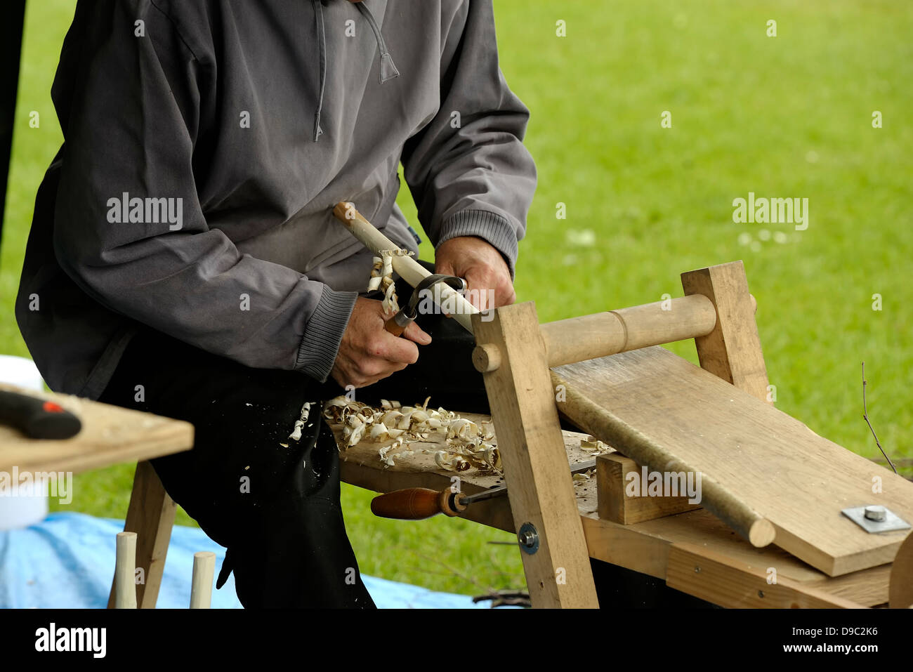 A man at a craft show demonstrating how to make broom handles the old