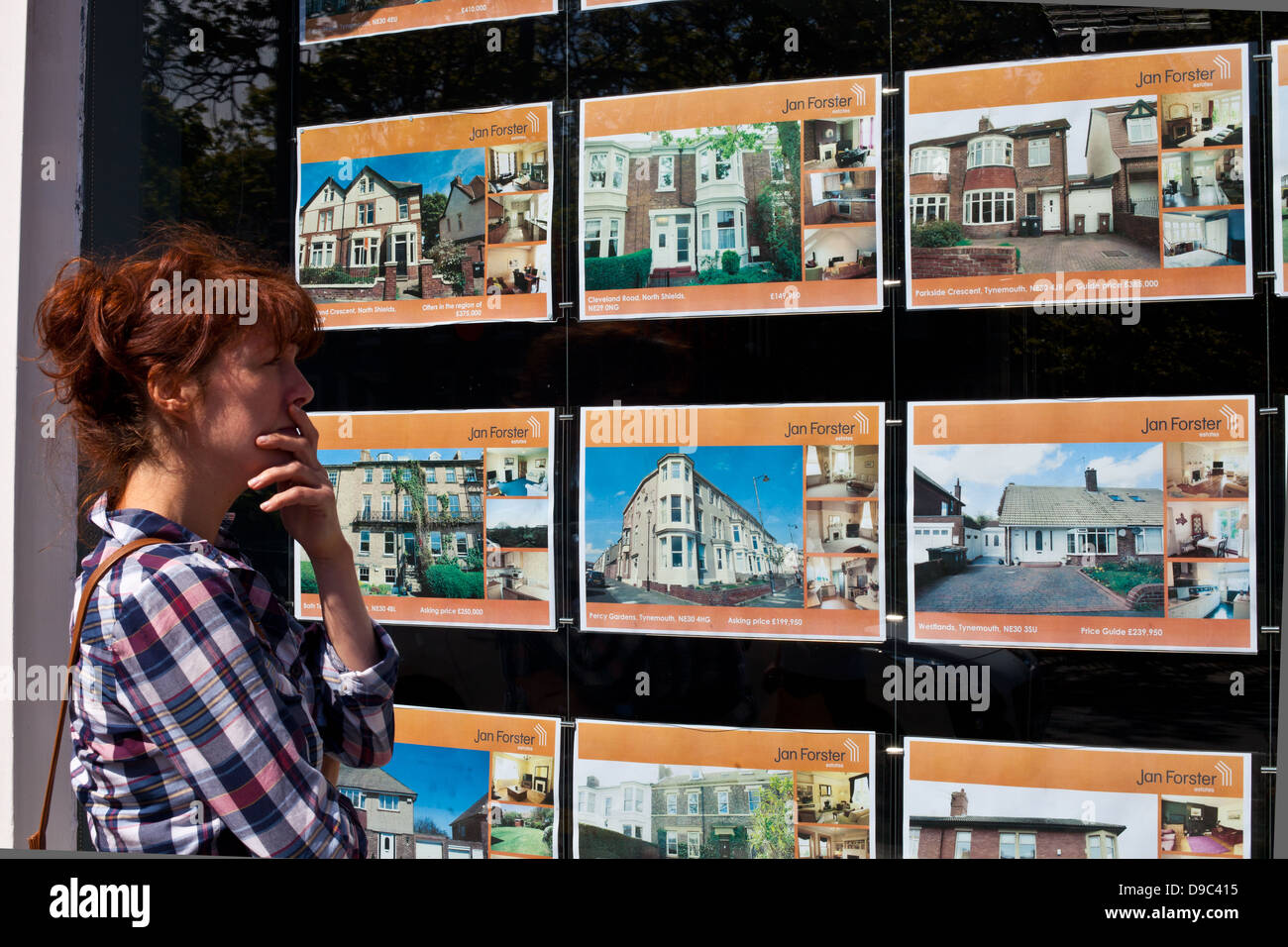 Woman looking in estate agents window Stock Photo