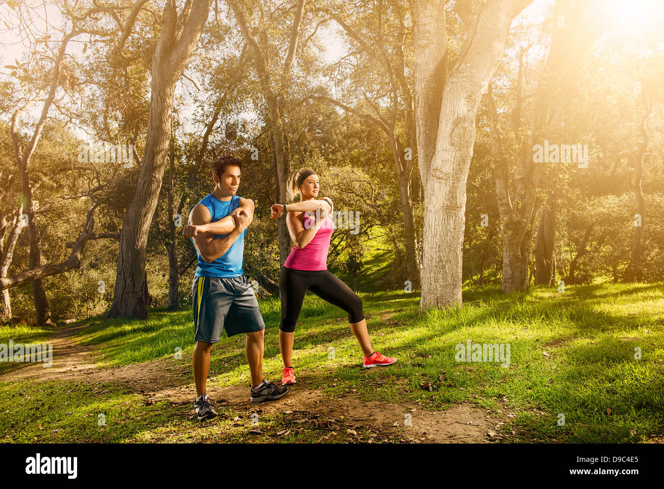 Two people exercising in forest doing warm up stretches Stock Photo