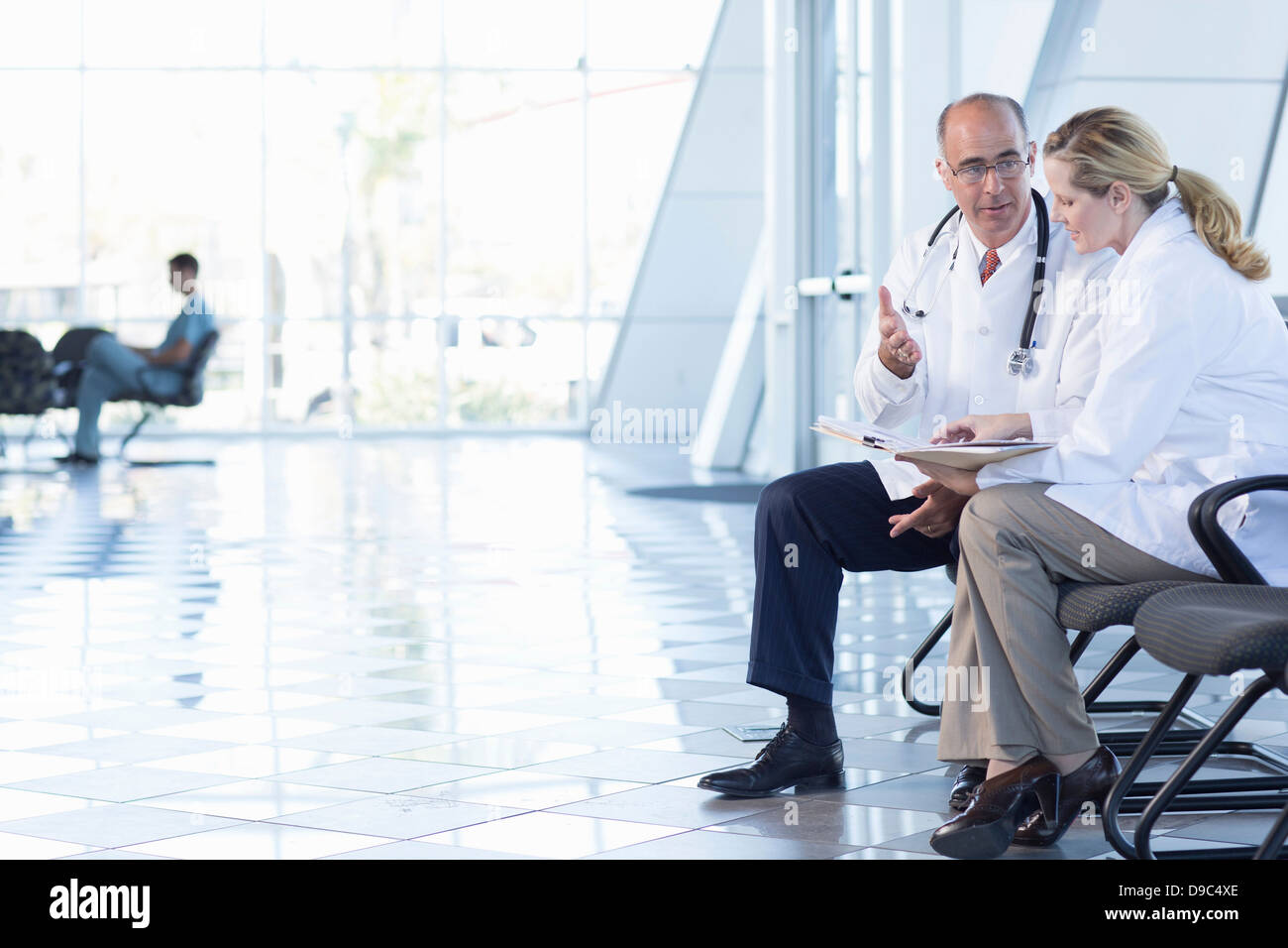 Male and female doctors sitting on chairs Stock Photo