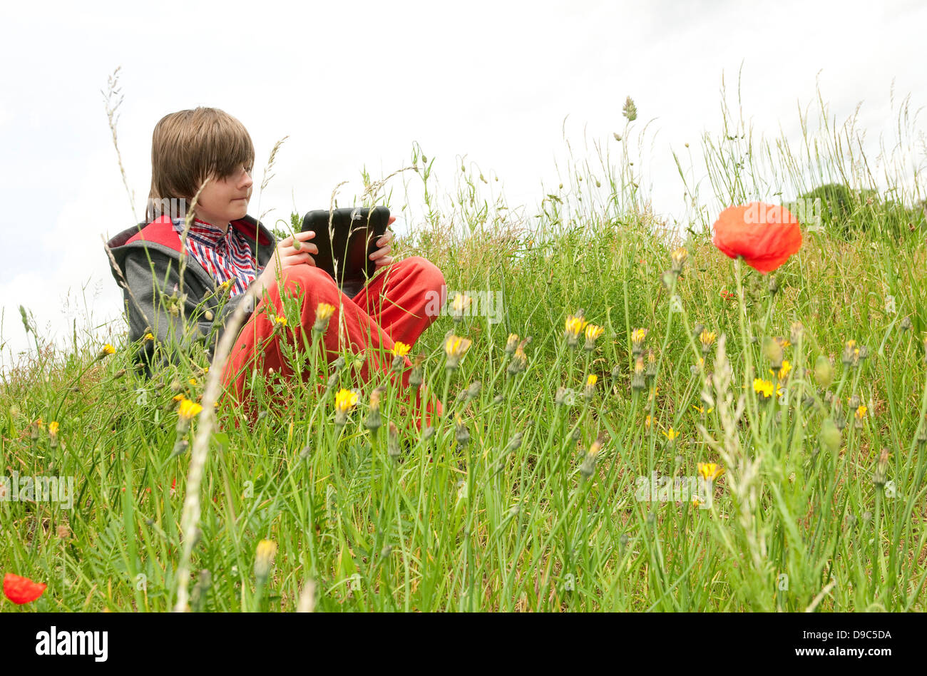 young male boy using ipad mini tablet computer in countryside Stock Photo