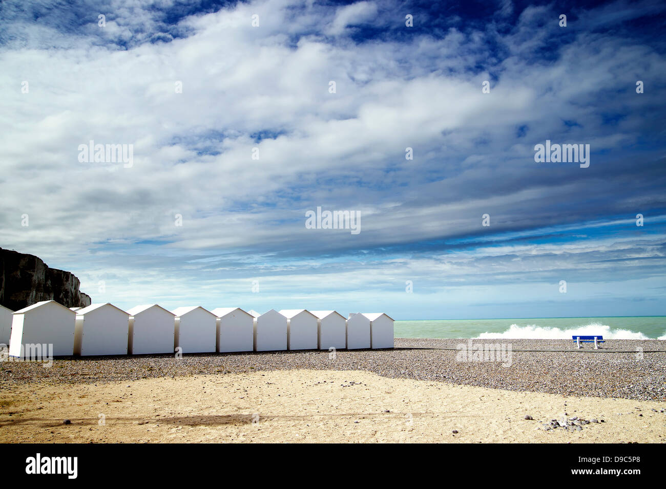 White beach huts in a row on shingle beach Stock Photo