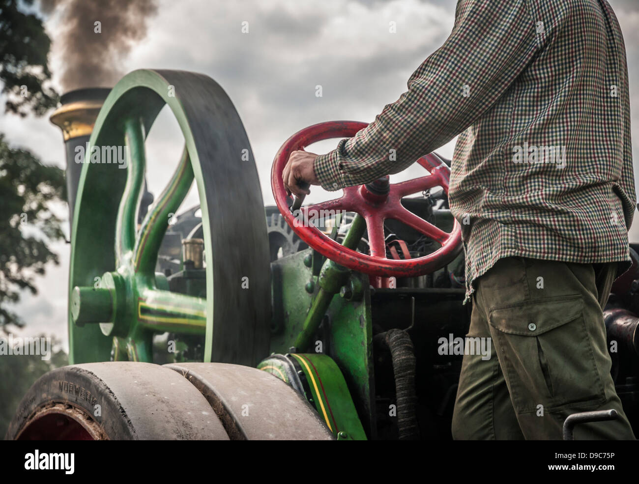 Steam traction engine being driven by a man surrounded by dirty smoke ...