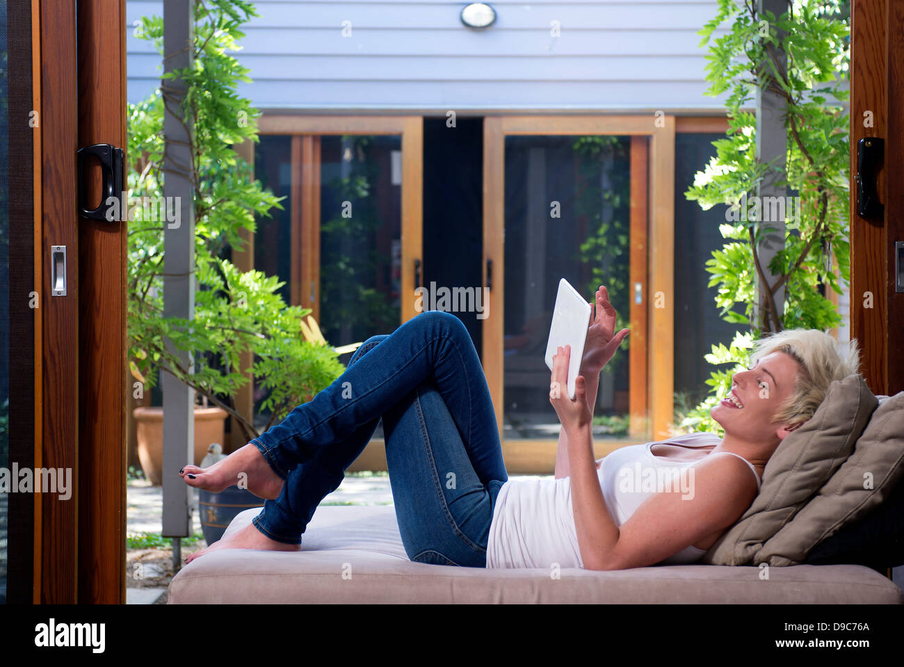 Young woman on sofa using digital tablet Stock Photo - Alamy