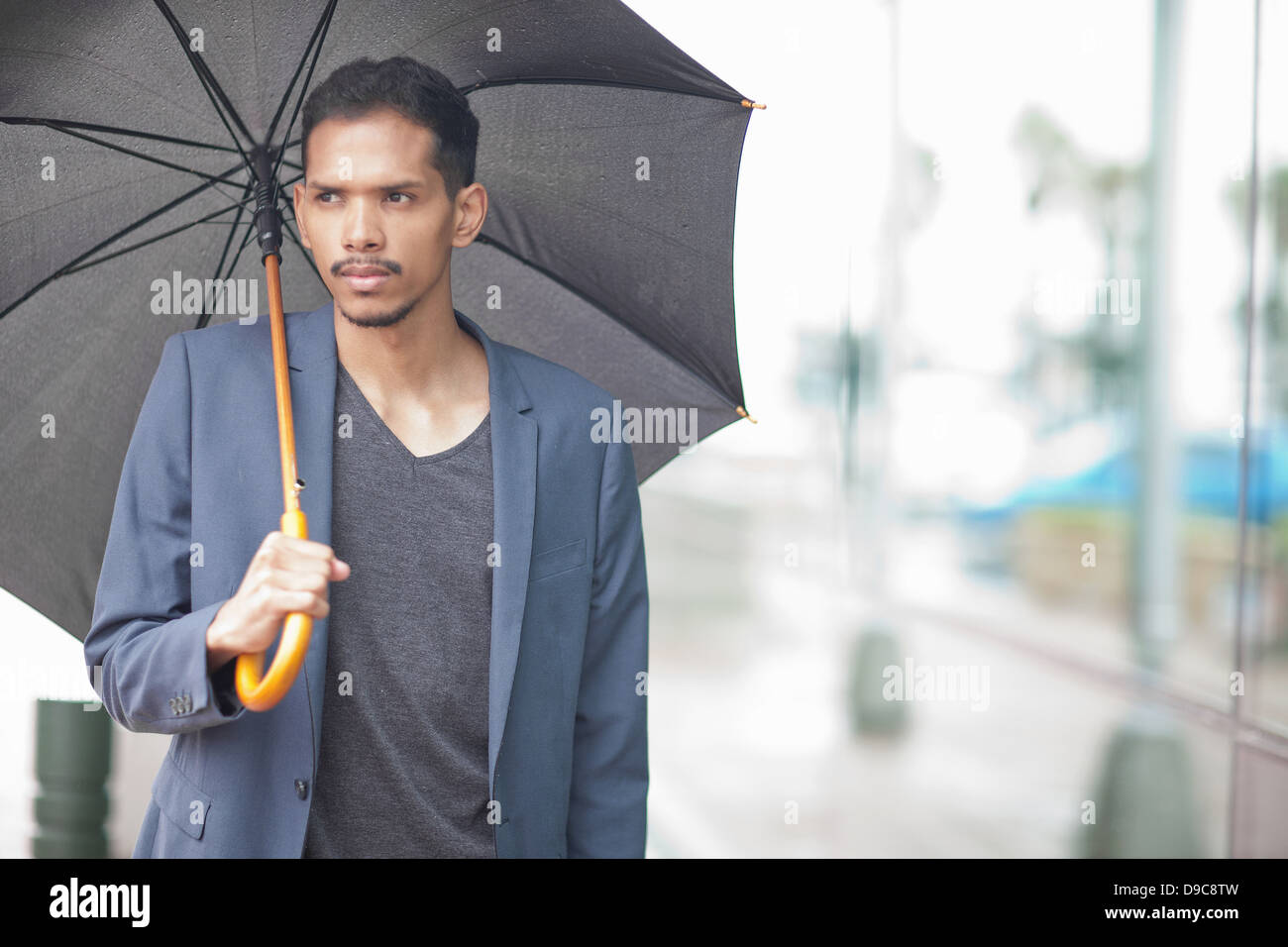Young man holding umbrella Stock Photo - Alamy