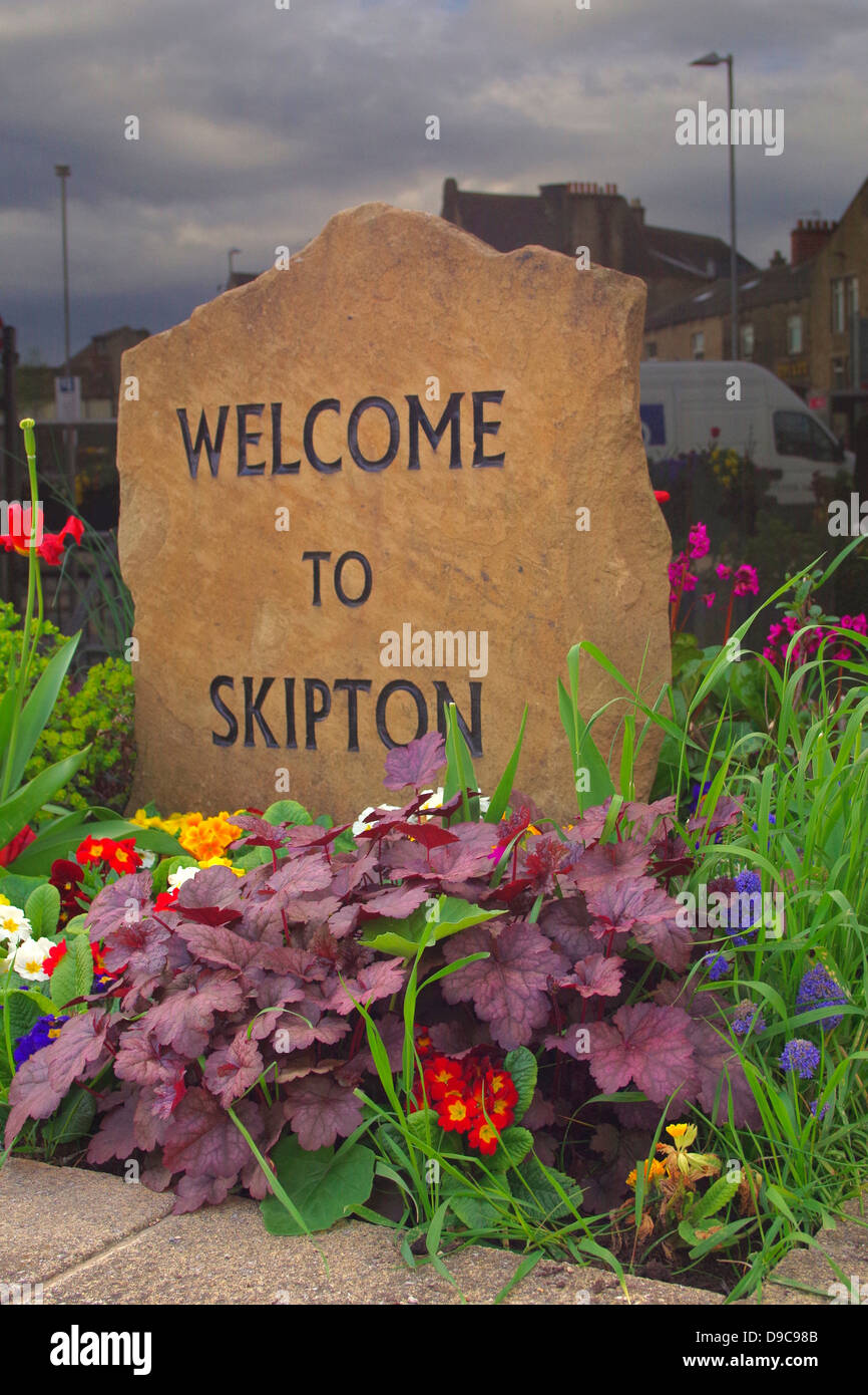 Floral display and stone welcome to Skipton Plaque. Stock Photo