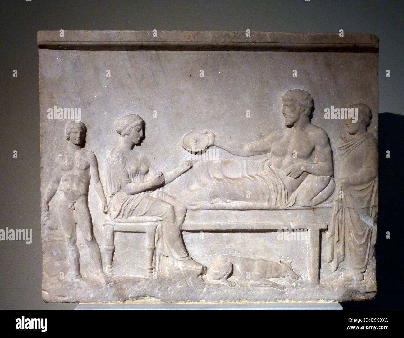 Votive relief, Pentelic marble, found in the Asklepieion of Piraeus.  It represents a funerary banquet.  The heroised dead reclines on a kline, holding a phiale in his right hand. End of the 5th century BC Stock Photo