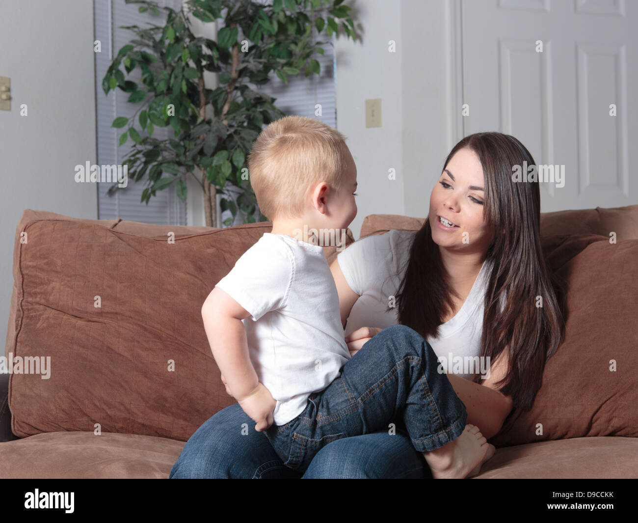 Mother and her young son sitting on the couch together at home in lifestyle setting casually playing together loving and bonding Stock Photo