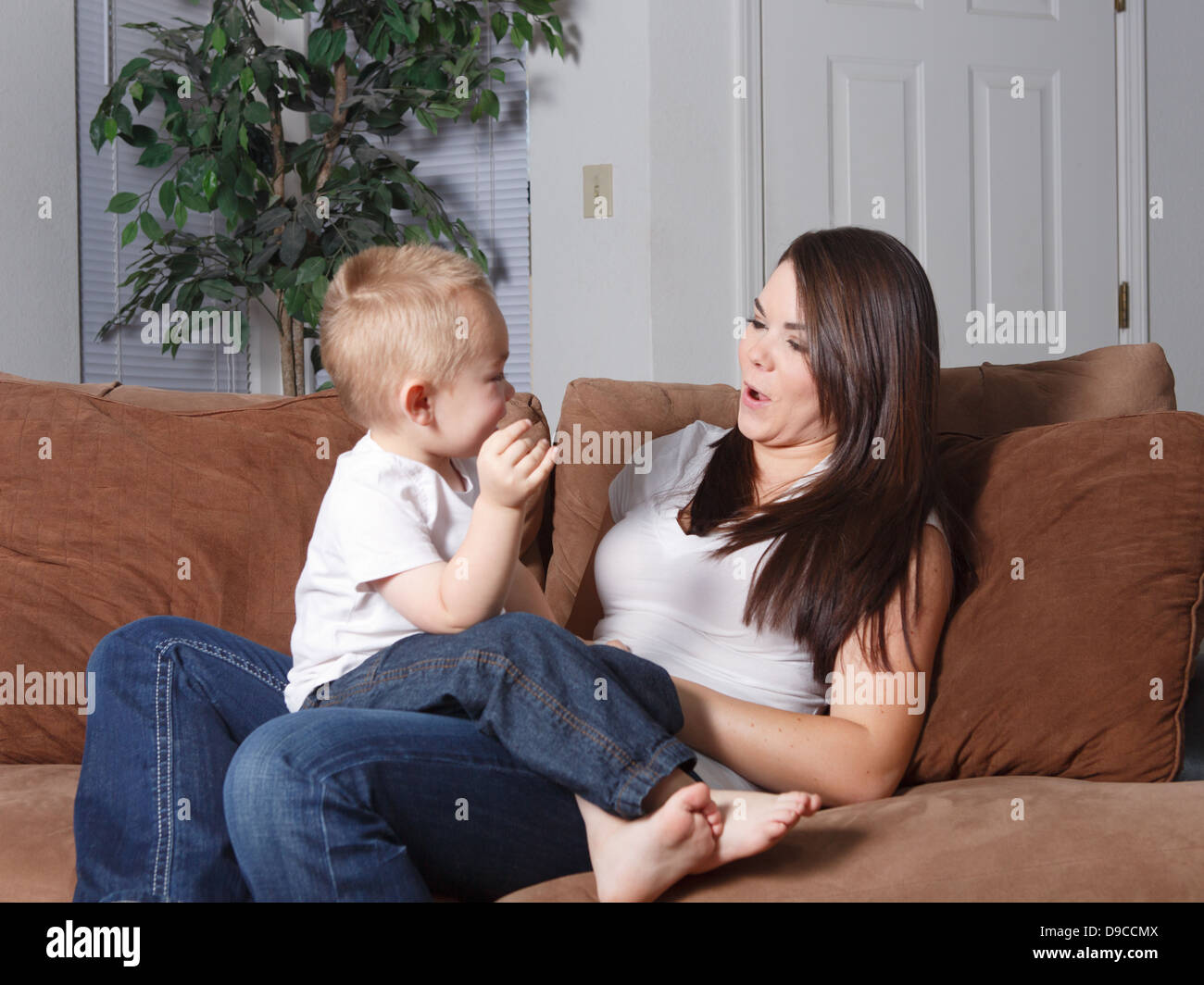 Mother and her young son sitting on the couch together at home in lifestyle setting casually playing together loving and bonding Stock Photo